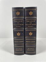 Spines of volumes one and two showing black leather binding with gilt lettering and maple leaf motifs