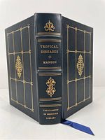 Full leather bound book with gilt lettering and decoration on covers and spine, blue silk bookmark visible.