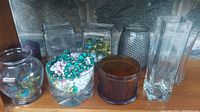 Image showing assorted glass vases and jars with decorative beads and marbles inside on a surface.