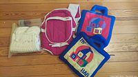 Pack including diapers in transparent bag, pink Playskool baby carrier, one baby bottle, and two foldout baby playmats with ABC prints.