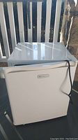 Front view of the smooth white Emerson mini refrigerator with power cord visible.
