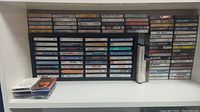 Overall view of cassette tapes organized on shelves and in holders, showing variety of titles and artists.