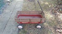 Side view of the vintage Radio Flyer wagon showing wooden slats, red metal base with Radio Flyer branding, and wheels.