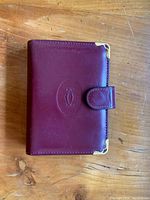 Exterior front view of Cartier burgundy leather address book showing embossed logo and gold-tone corner protectors