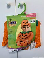 Photo of the baby pumpkin costume in original packaging showing the jumper, headpiece, and booties for 12-18 months old.