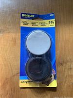 Pack of 4 Shepherd Slideglide furniture sliders in original packaging, two white and two black, 1-3/4 inch size