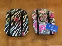 Two large pencil cases, one zebra stripe with floral accents and one graffiti style with pink, black, and white patterns, both new with zippers.