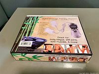 Box of the digital massage therapy machine showing branding, features, and suggested use locations.