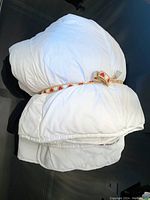 Photo shows a white queen size duvet neatly folded and tied with a decorative red-heart ribbon on a black surface, illustrating the condition and appearance.