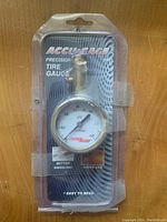 New Accu-Gage precision tire gauge in original blister packaging with clear plastic and black backing card with white and orange text.