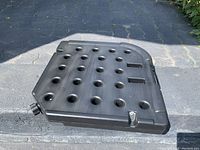 Top view of a single black resin umbrella base showing multiple holes, handles, and fill port.