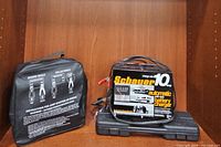 Schauer 10 amp automatic battery charger unit placed on top of wrench set case displaying front panel and cables.