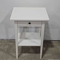 Front view of white 1-drawer side table showing drawer closed and lower shelf.