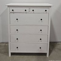 Front view of white Ikea Hemnes dresser with all drawers closed showing six drawers and black round knobs.