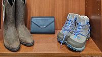 Pair of western leather boots, black clutch, and taupe suede boots with blue laces