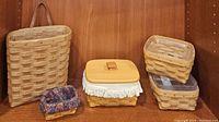 Five Longaberger baskets including a wall basket, nested baskets, a lined basket and a basket with wooden lid