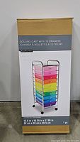Front view of unopened cardboard package showing image of rainbow rolling cart with 10 drawers and size measurements.