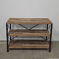 Front view showing three wooden shelves with natural wood grain on a black metal frame with X crossbars.