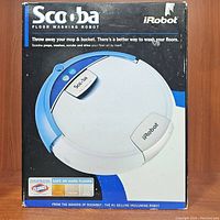 Front view of boxed iRobot Scooba floor washing robot with key product branding and usage claims.