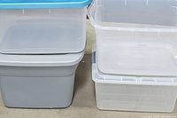 Close-up of gray and clear plastic storage containers stacked, showing lids and container walls.