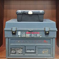 Large gray Phantom Pro toolbox stacked below small black toolbox on shelf