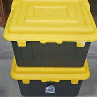 Photo showing stacked view of two heavy-duty utility totes, black body with yellow lids, in used condition.