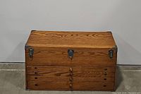 Front view of the closed wooden toolbox showing metal latches and corner protectors.