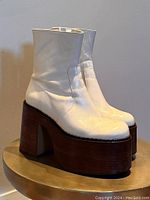 Front and side angle showing the off-white leather boots with thick wooden platform soles and heels.