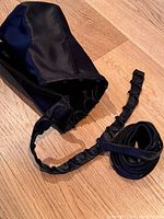 Black duchess satin corset sew-in kit showing the smooth fabric, attached loops and hooks, boning, and satin ribbons for tightening and securing.