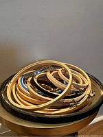 Stack of round wooden embroidery hoops of various sizes and some metal hoops seen on a table