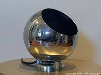 Chrome eyeball lamp showing reflective spherical exterior and black interior with socket