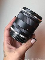 Minolta lens extender held in hand showing focus and length markings such as No. 2 and No. 3.