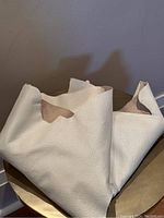 Large piece of folded off-white pebbled leather hide showing both grain and flesh sides on a round table.