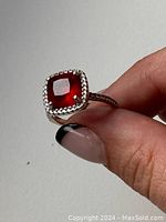 Front view showing cushion-cut deep red ruby set in sterling silver with cubic zirconia stones surrounding the center stone.