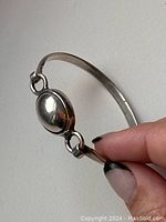 Close-up photo showing polished oval centerpiece and part of the silver band of the bracelet.