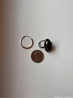 Photo showing the sterling silver ring with oval decorative stone and single sterling silver hoop earring next to a quarter for scale
