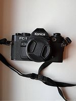 Front view of vintage Konica FC-1 film camera with lens cap and strap attached.