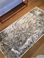 Full view of the large black and white educational poster laid flat on the floor, showing detailed illustrations on climate change and resource extraction.