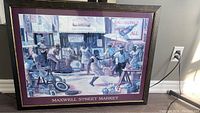 Framed painting 'Maxwell Street Market' showing a busy street market scene with people and market stalls. Close-up view.