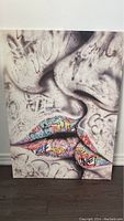 Front view of stretched canvas artwork showing graffiti style lips and monochrome face background