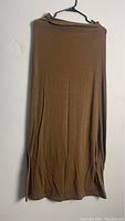 Brown wrap around skirt hanging on a black hanger, displayed against a white wall.