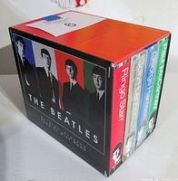 Box set container with stylized Beatles portrait and colored stripes for each member