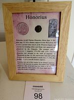 Framed ancient Roman coin with general view of wooden frame and informational plaque about Emperor Honorius.