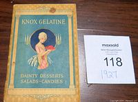 Front cover of Knox Gelatine brochure showing vintage illustration of woman holding red gelatin dessert, with title text and decorative border.
