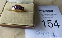 Gold-tone ring with two square-cut purple amethyst stones in a box, size 6.