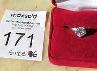 Photo showing the solitaire ring in a red jewelry box alongside a lot tag indicating size 6.