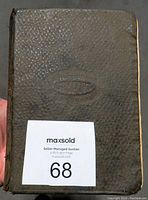Front cover of the black textured hardcover book with embossed oval design
