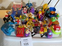 Top view of various vintage toy collectibles including characters from M&M's, Star Trek, Pez, Disney, and McDonald's, displayed on a white table.