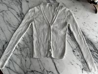 Top view of white ribbed cardigan laid flat on marble surface showing front side, V-neck, and long sleeves