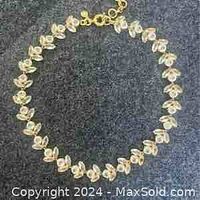 Full circular view of necklace showing clear crystal-like links in a floral pattern on a dark fabric background.